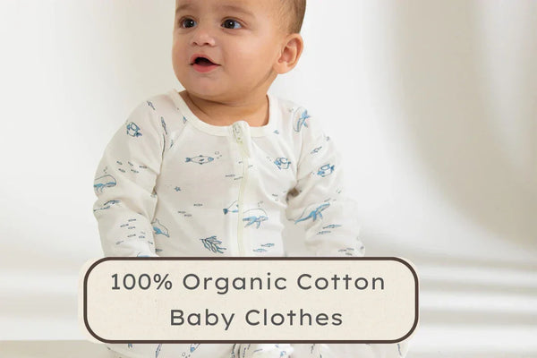 Baby wearing white organic cotton clothes with blue ocean animals print on plain background