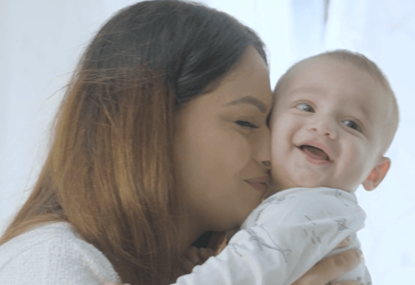 Mother smiling and holding happy baby in cozy indoor setting