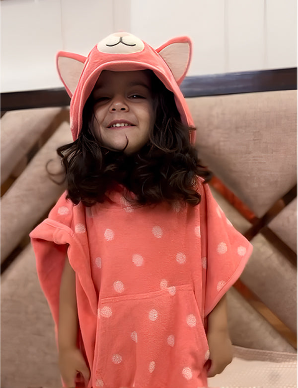 Smiling girl wearing pink hooded towel with animal ears and white polka dots indoors