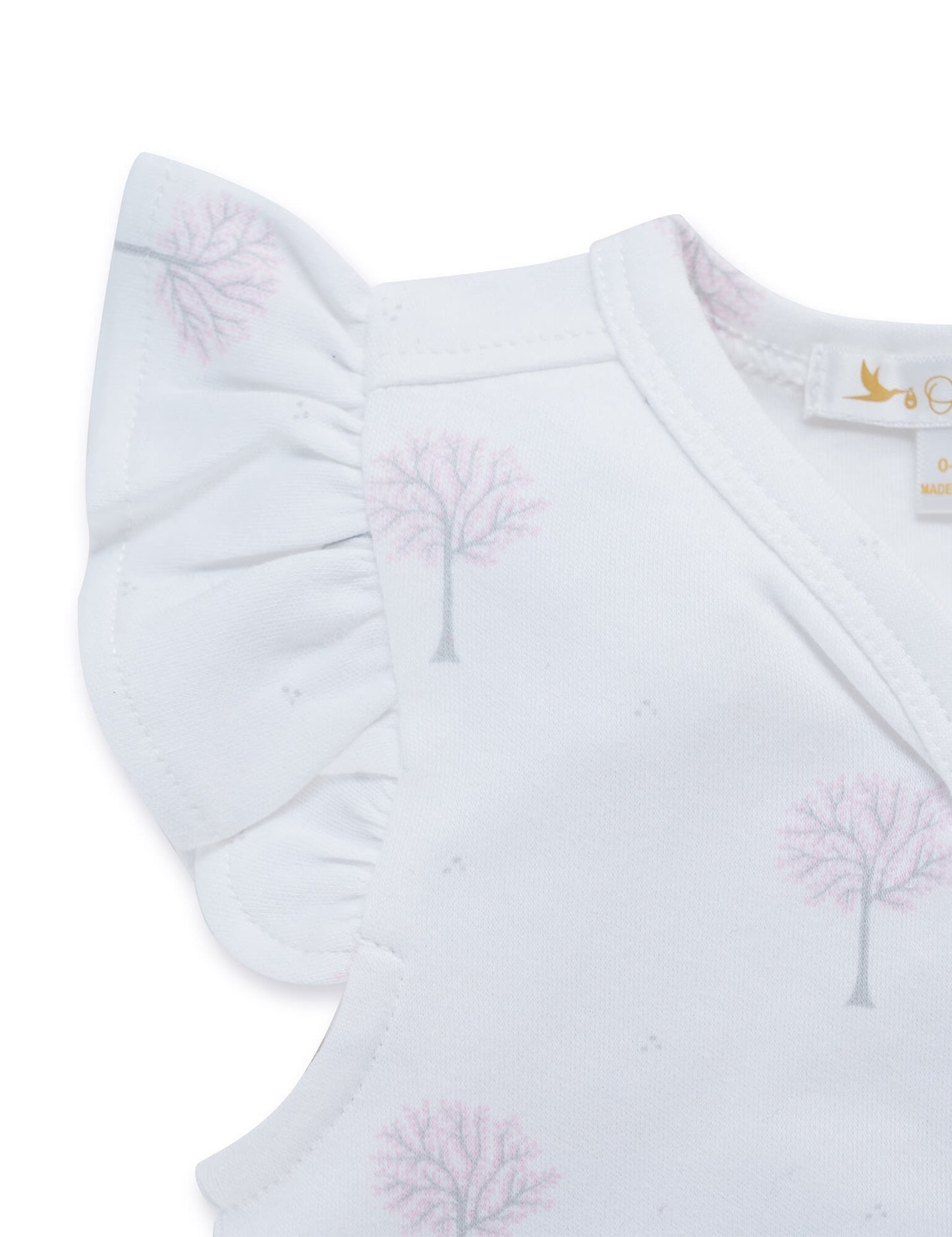 Close-up of white baby dress with pink tree print and ruffled cap sleeves