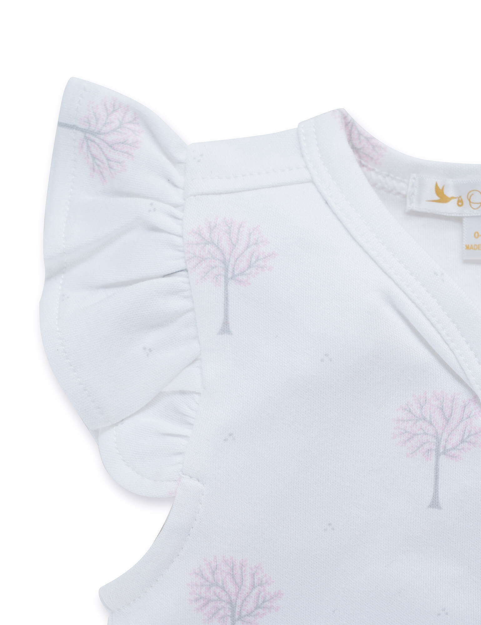 Close-up of white baby dress with pink tree print and ruffled cap sleeves