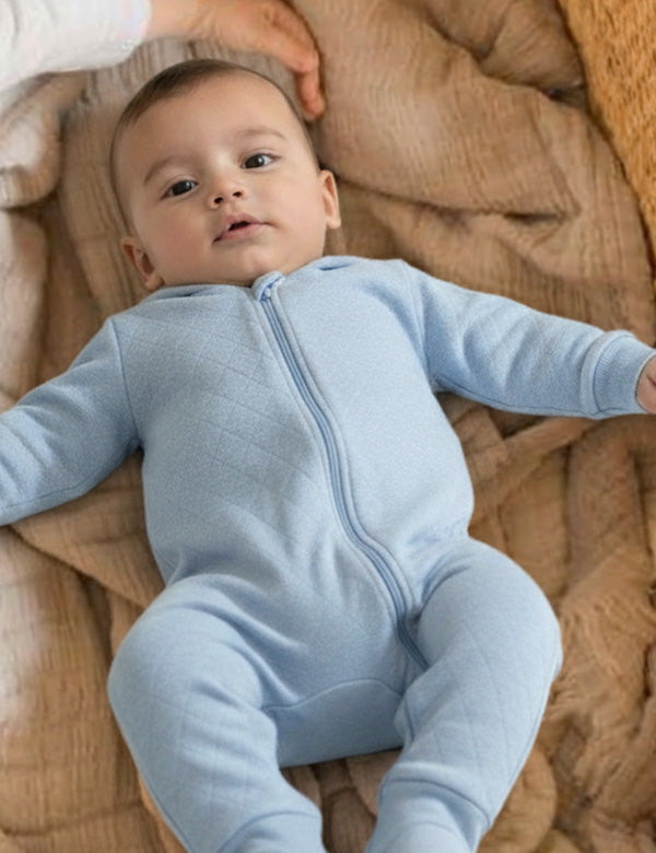 Baby wearing soft blue quilted organic cotton romper – cozy winter outfit.