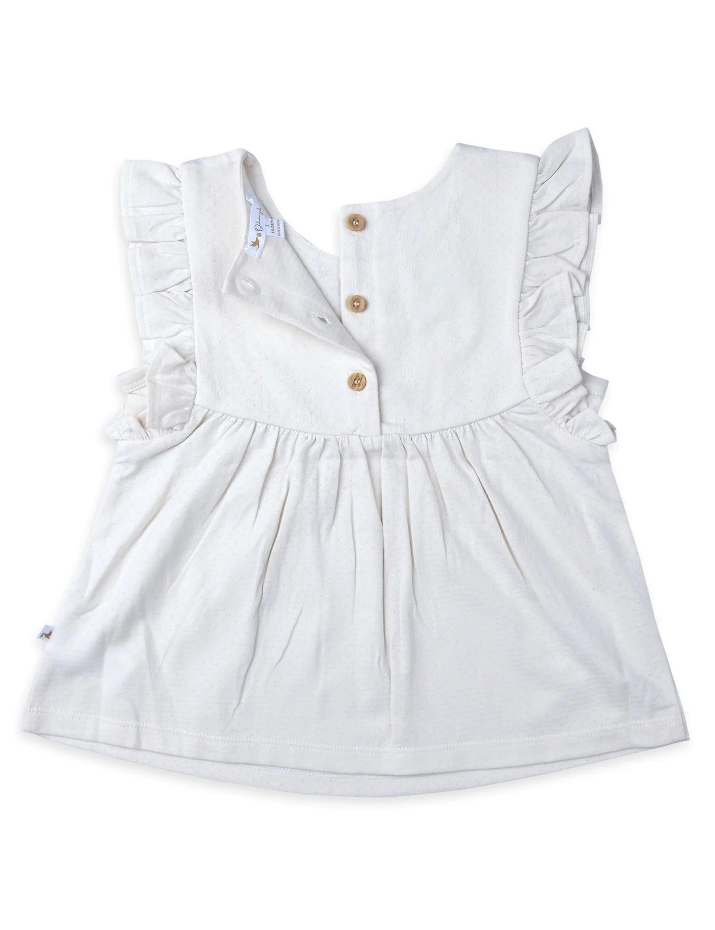 Back view of white baby tunic top with embroidered fabric, ruffle sleeves, and wooden buttons