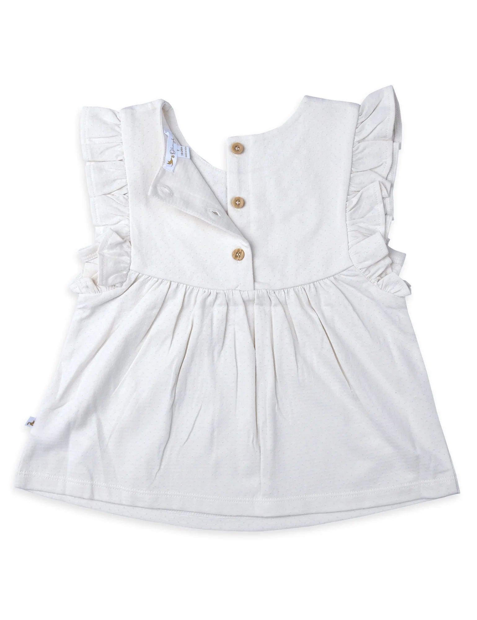 Back view of white baby tunic top with embroidered fabric, ruffle sleeves, and wooden buttons