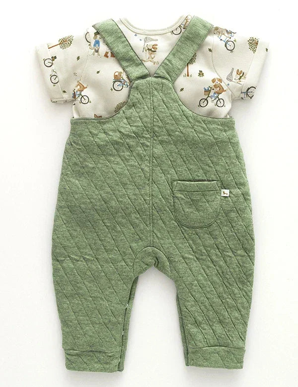 Back view of olive green quilted baby boy dungaree with white printed short-sleeve shirt featuring dogs on bicycles
