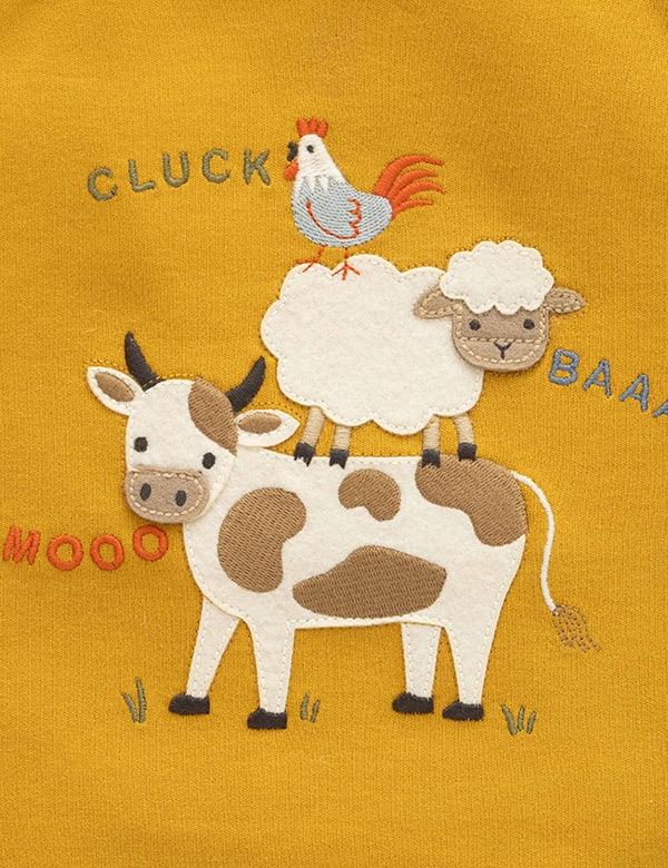 Close-up of cow, sheep, and rooster embroidery on mustard baby top