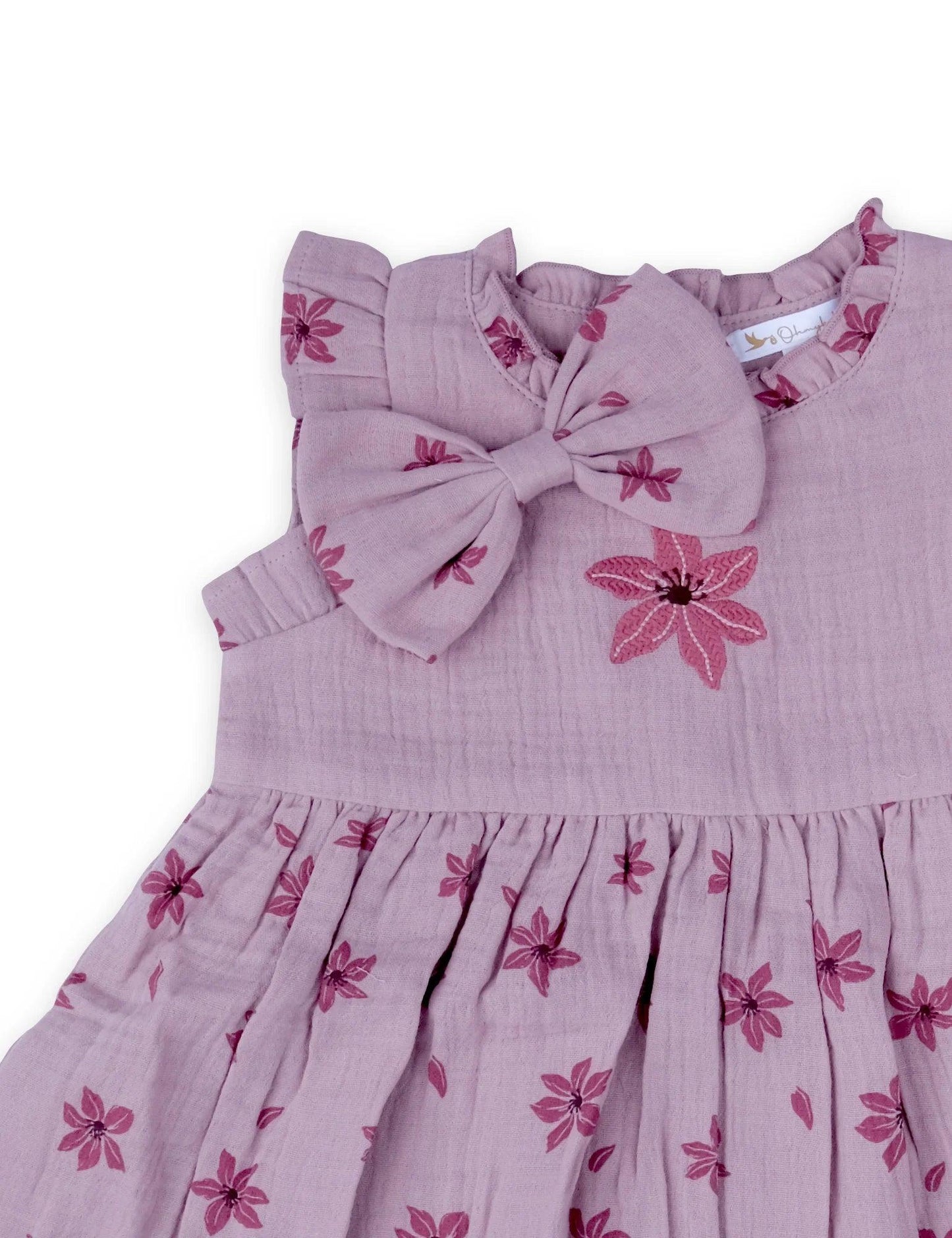 Close-up of pink floral baby dress with ruffled sleeves and matching bow detail