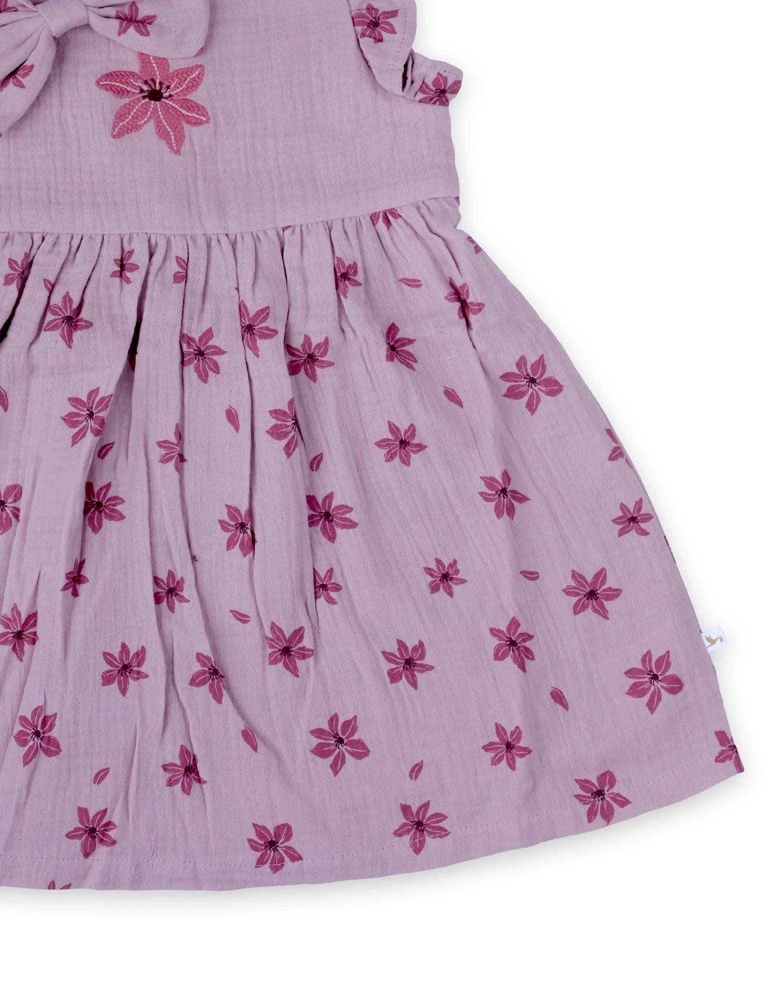Close-up of lilac organic cotton baby dress with dark pink floral print and bow details