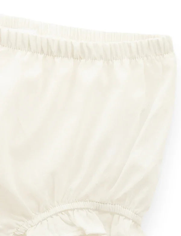 Cream-colored cotton baby nappy with elastic waistband and leg openings on white background