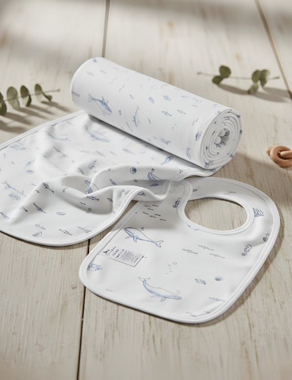 White baby bib and blanket set with blue ocean animal prints on wooden surface