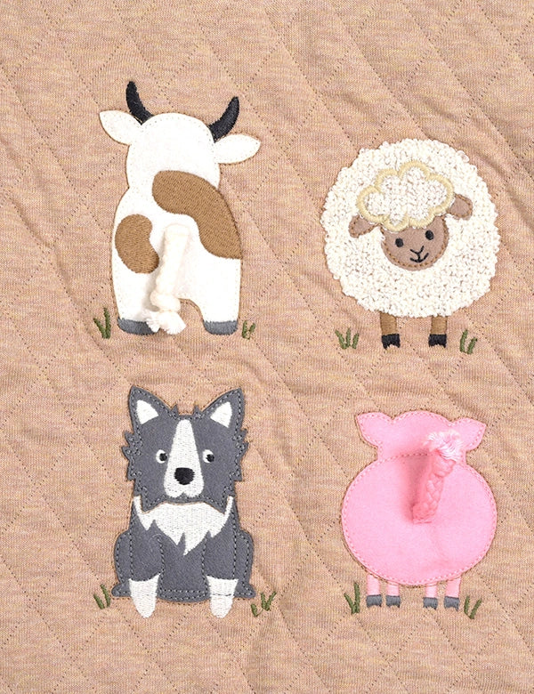 Quilt with appliqué of a cow, sheep, and dog on a beige background