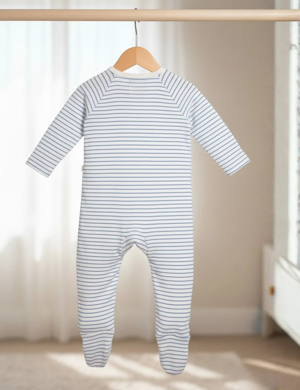 Striped baby onesie hanging on a wooden hanger against a neutral background
