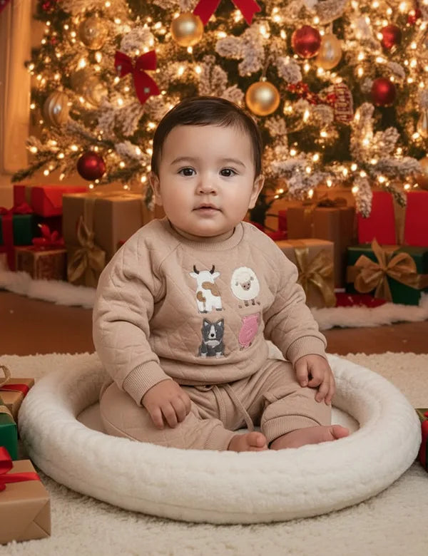 Child sitting on a cushion in front of a decorated Christmas tree with presents.