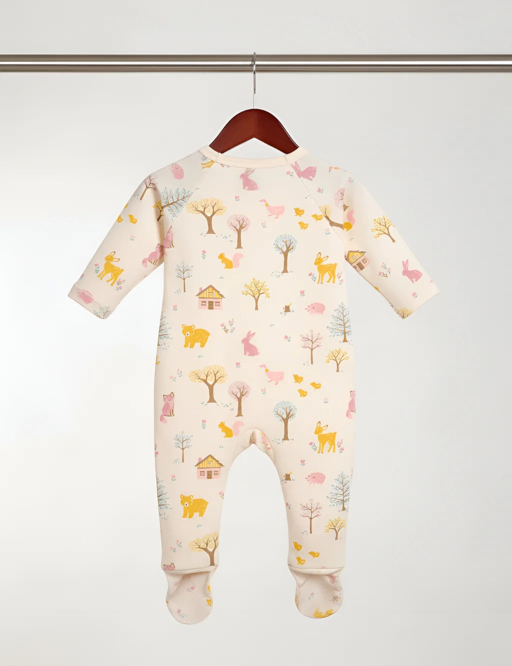 Baby onesie with animal and nature pattern hanging on a wooden hanger against a white background
