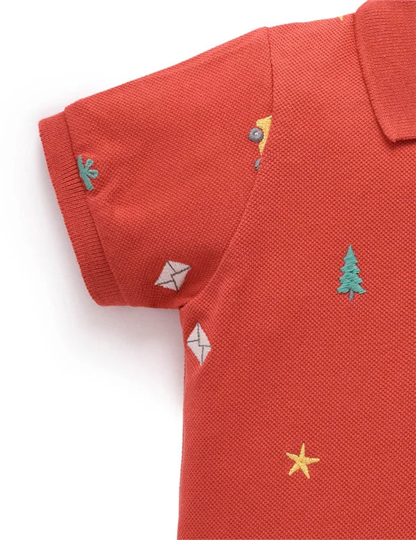 Red polo shirt with embroidered designs on a white background