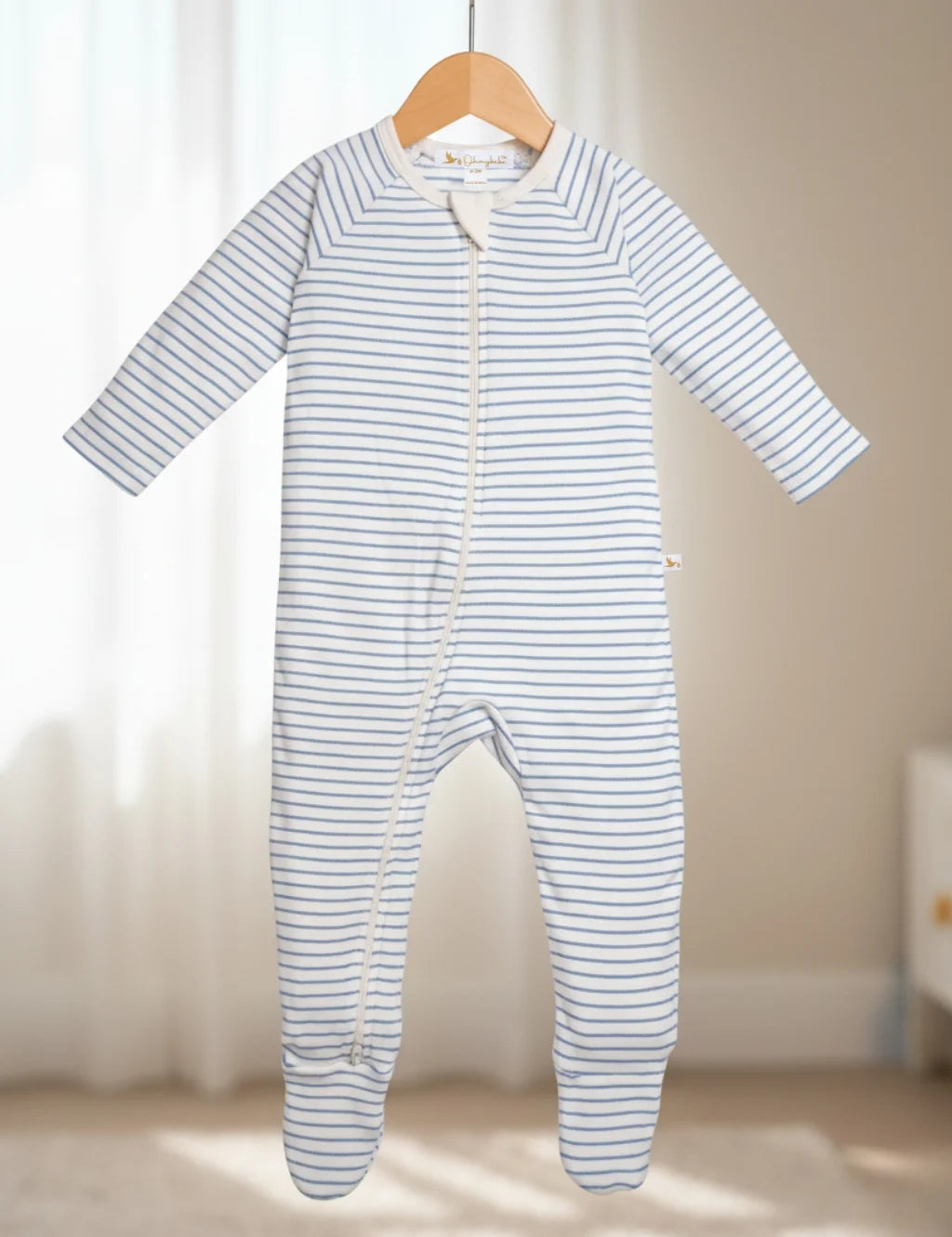 Striped baby onesie hanging on a wooden hanger against a neutral background