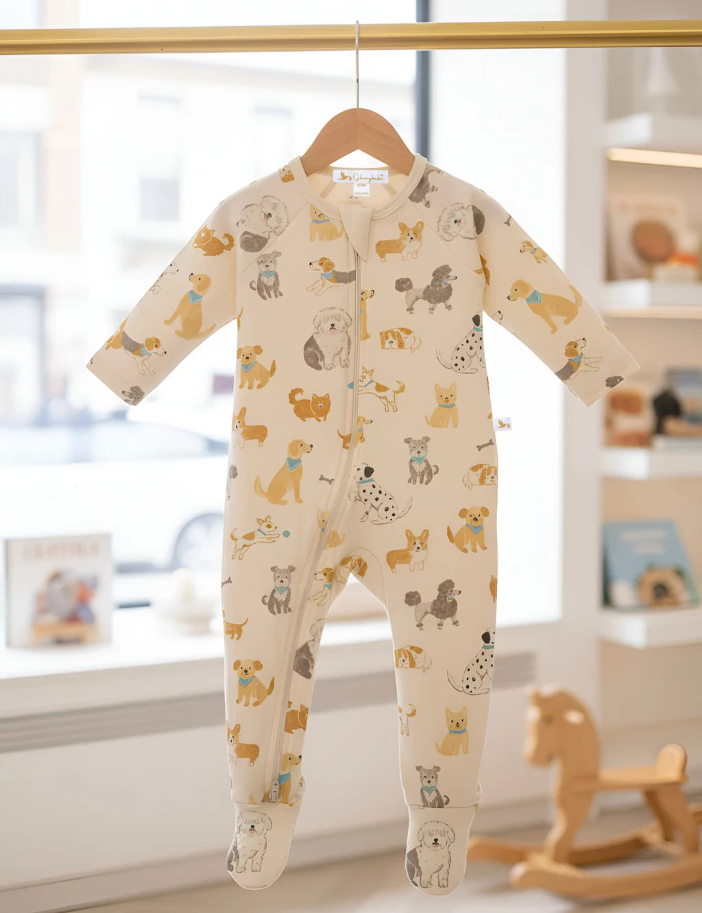 Baby onesie with dog pattern hanging on a hanger in a nursery.