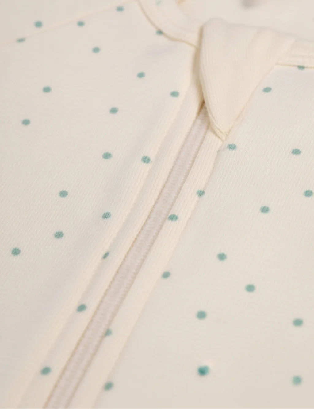 Close-up of a baby garment with a zipper on a polka dot background