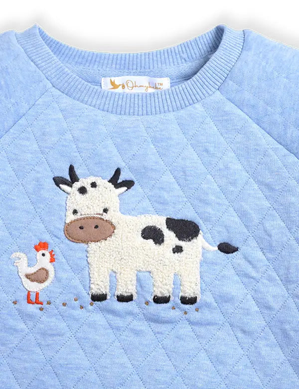 Close-up of cow and chicken embroidery on blue organic quilted baby winter sweatshirt. 