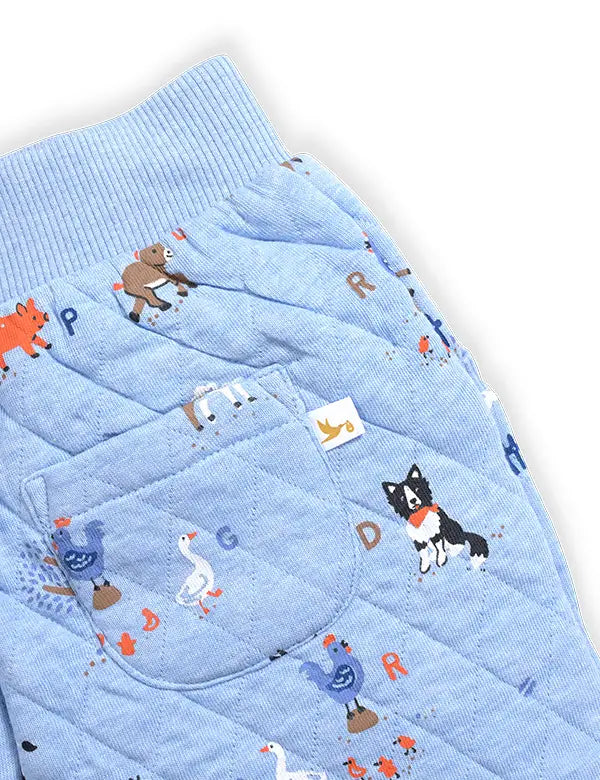 Close-up of blue baby winter joggers with quilted fabric and animal print featuring dog, goose, and bear
