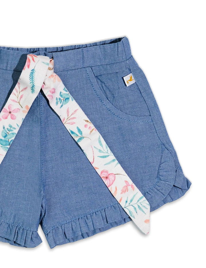 Detail of the denim-look baby shorts with a ruffled hem and a charming floral print sash tied at the waist. Shop stylish baby bottoms India.
