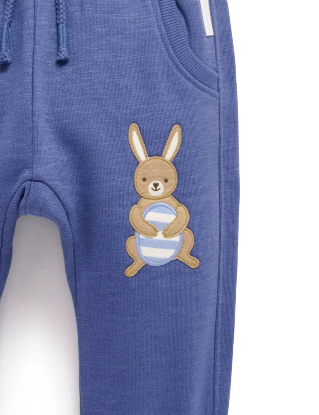 Close-up detail of the cute bunny holding a striped egg appliqué on blue baby fleece pants.
