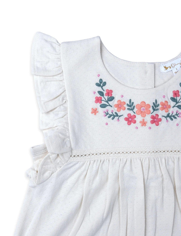 Close-up of the white baby tunic top featuring beautiful floral embroidery on the chest and delicate ruffle sleeves. Shop embroidered baby tops India.