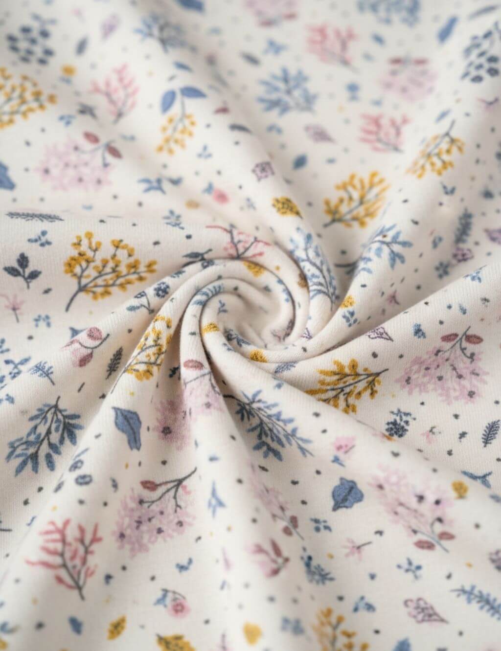 Close-up fabric detail of an organic cotton floral print romper showing the soft texture and botanical pattern.