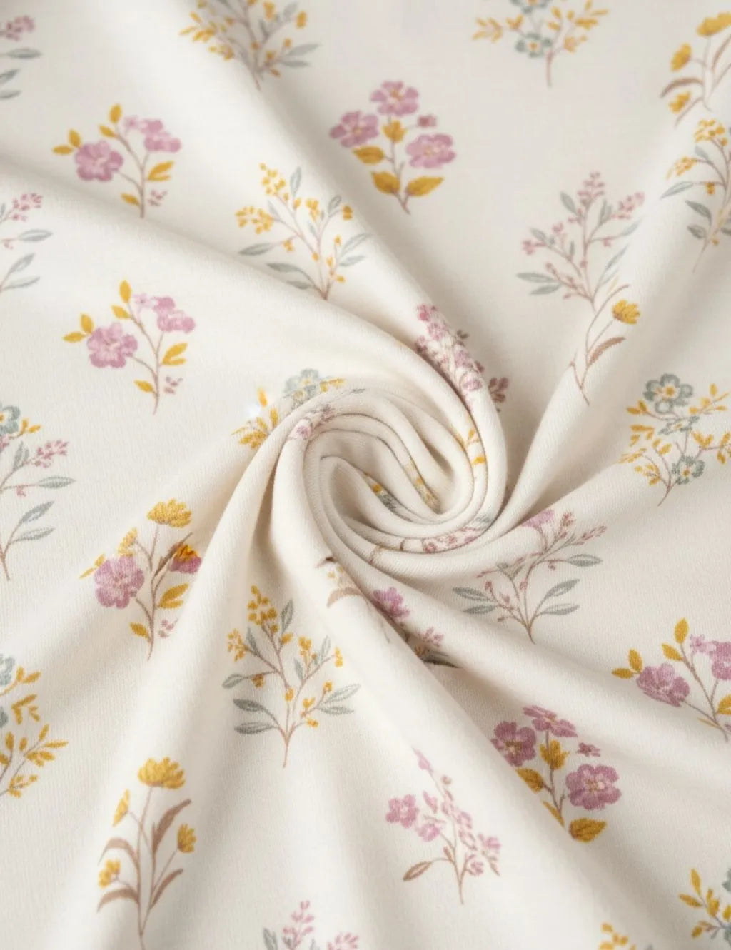 Close-up fabric detail of an organic cotton floral print romper showing the soft swirled texture and delicate floral botanical pattern.