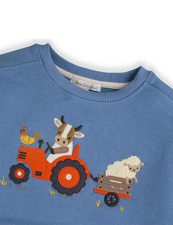 Blue sweater with embroidered farm animals including a cow driving a red tractor, a rooster, and a sheep in a trailer
