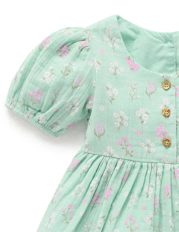 Mint green baby dress with pink and white floral print, puff sleeves, and wooden buttons