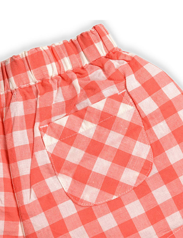 Close-up of peach and white gingham baby shorts with elastic waist and rounded back pocket