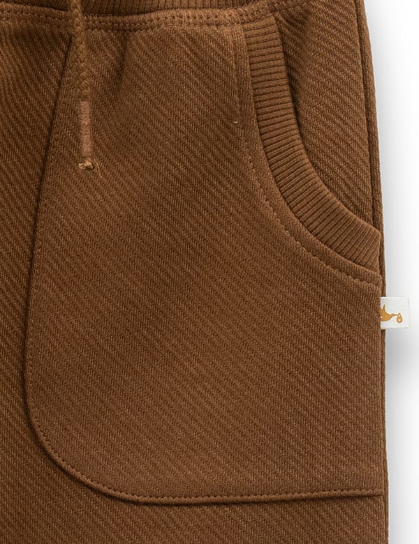 Close-up of brown baby jogger pants pocket with ribbed trim and fabric texture detail