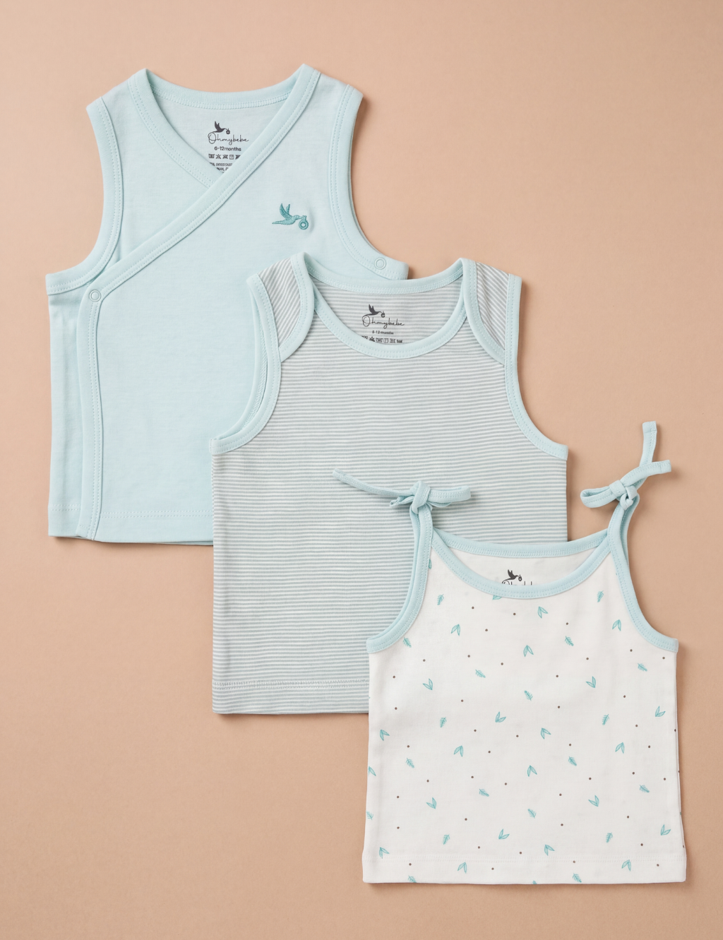 Flat lay view of three baby tank tops arranged diagonally in a set. From back to front: a solid mint green wrap-style tank top with a small embroidered bird on the left chest, a mint green tank top featuring thin horizontal white stripes and a side tie, and a white camisole tank top patterned with tiny mint green leaves and dots, finished with light blue trim and shoulder ties, all displayed against a plain beige background.