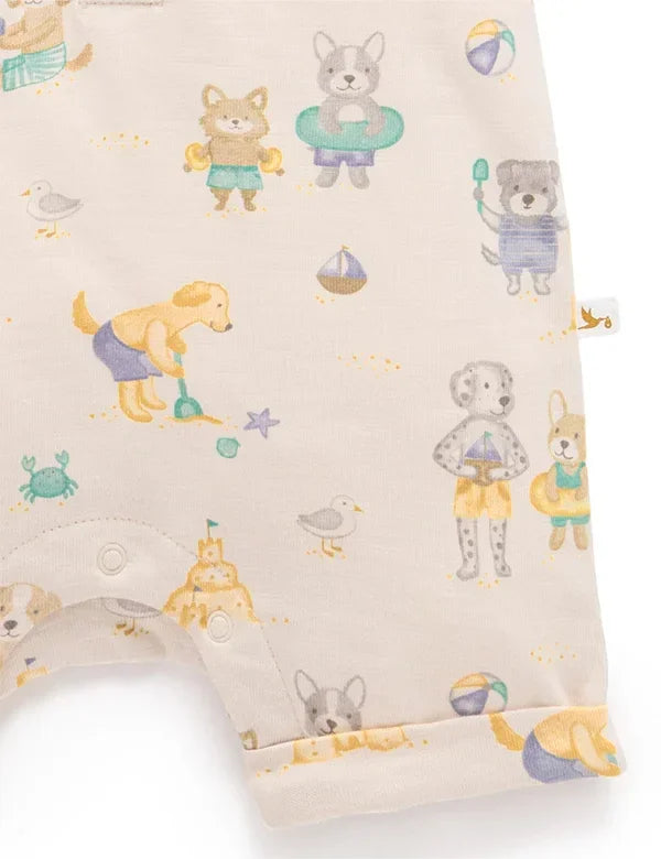 Close-up of baby romper fabric with colorful beach dogs print, sandcastles, and beach toys