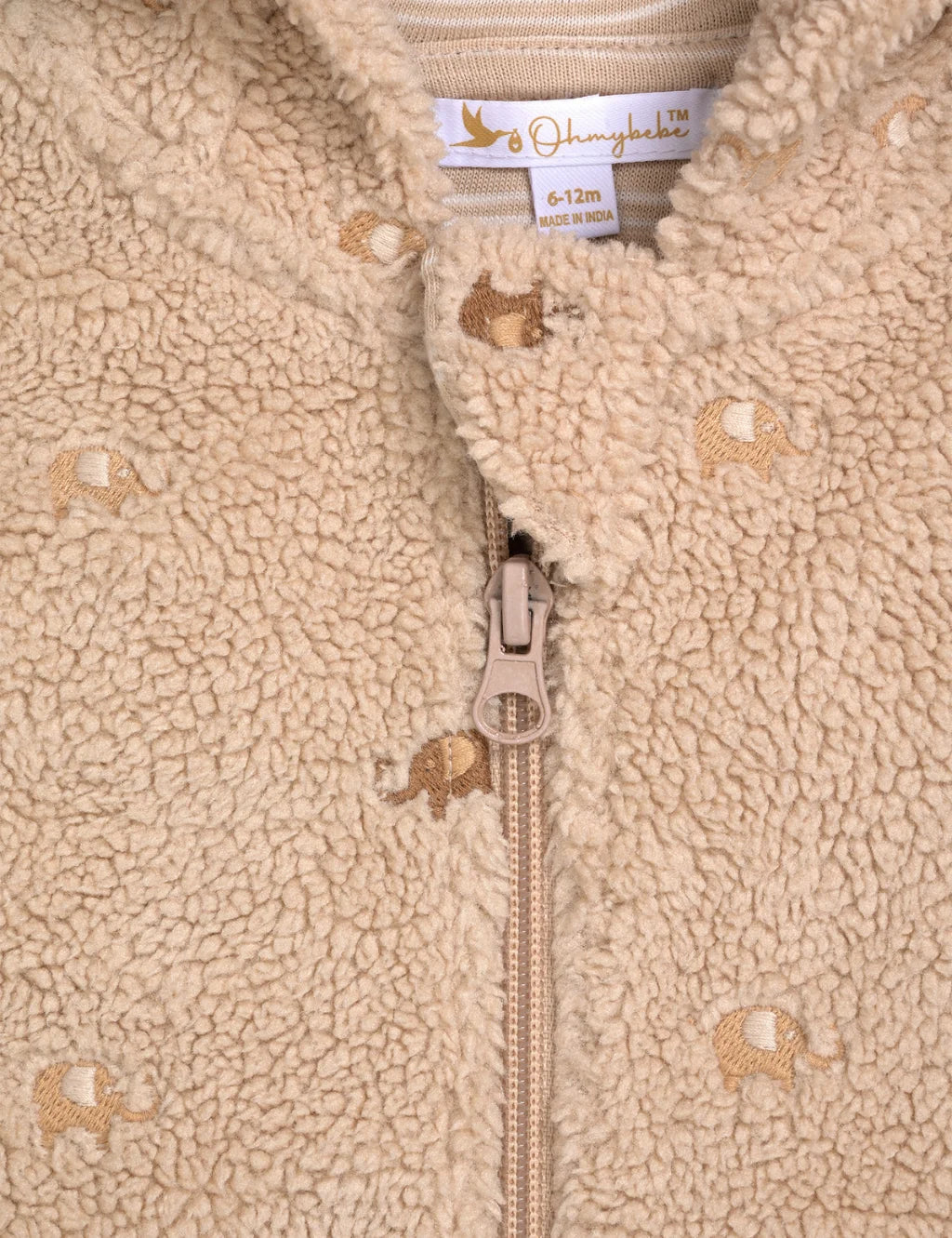 Close-up of a beige fleece jacket with a zipper and animal pattern, featuring a brand label.