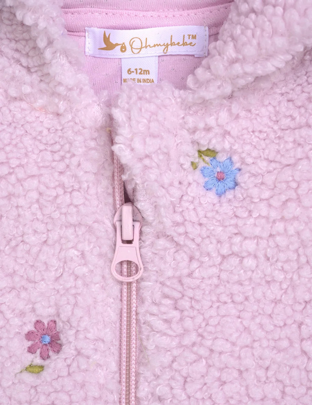 Close-up of a pink textured fabric with a zipper and floral embroidery, featuring the brand 'Oh My Love'.