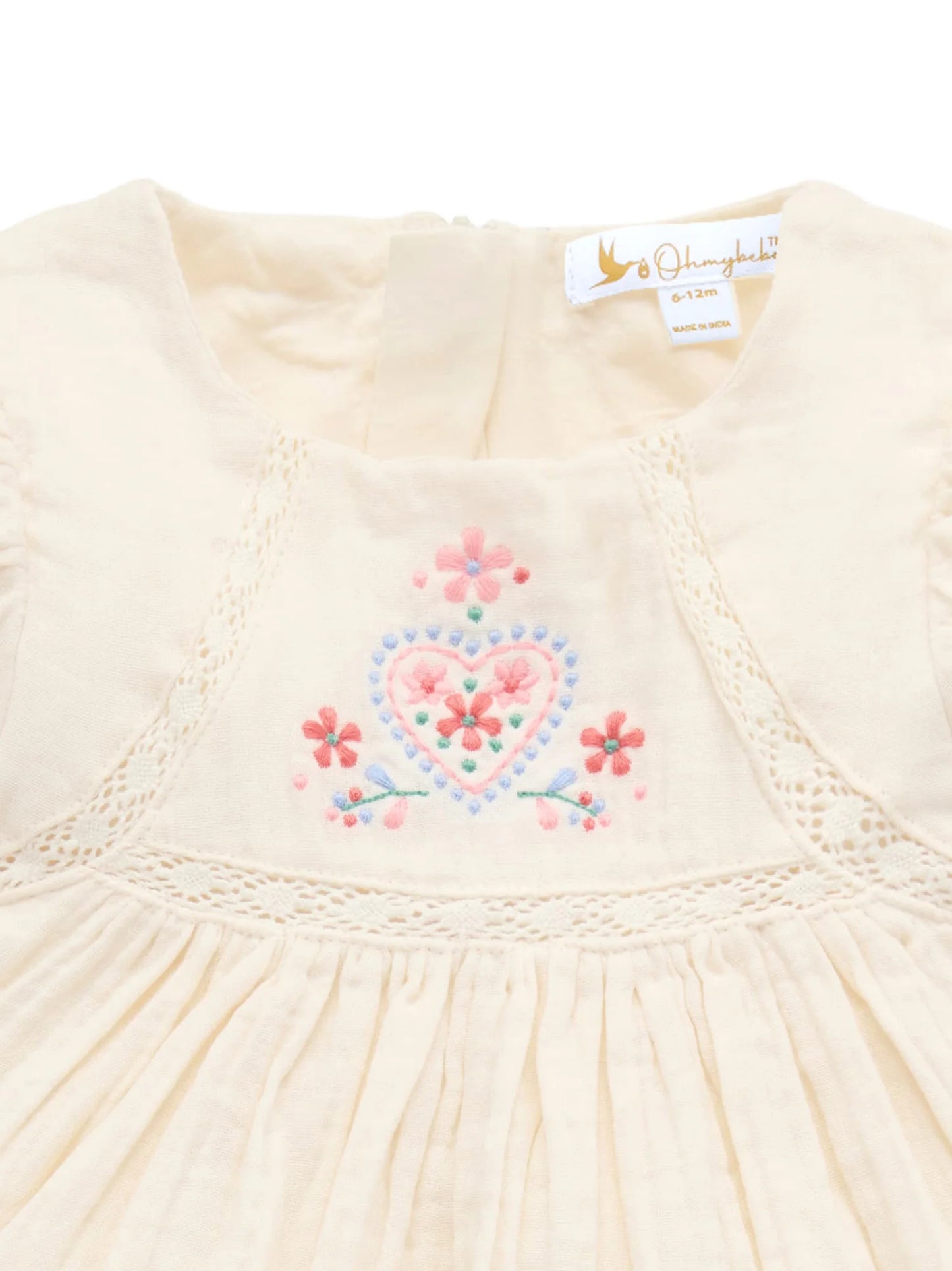 Cream-colored dress with floral embroidery and a visible brand label on a white background