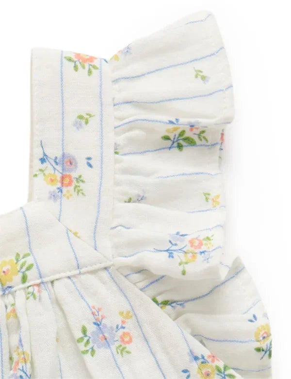 Close-up of white baby girl top with blue stripes and floral print featuring ruffle shoulder detail