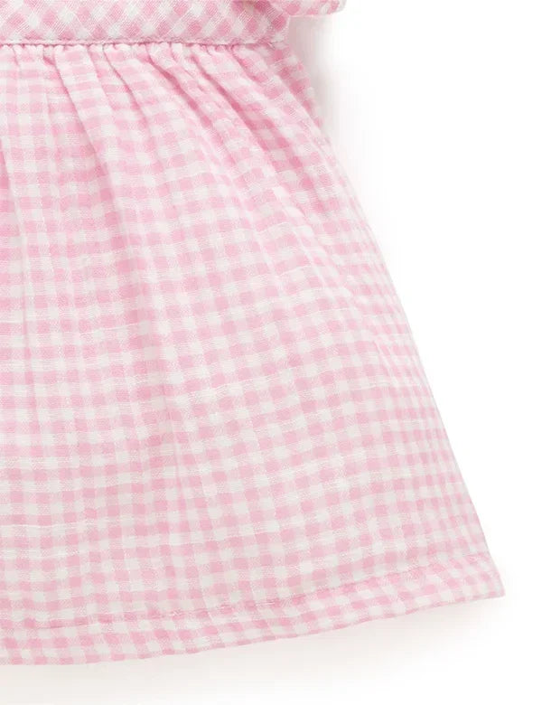 Close-up of a pink gingham cotton fabric with ruffle shoulder embroidery detail