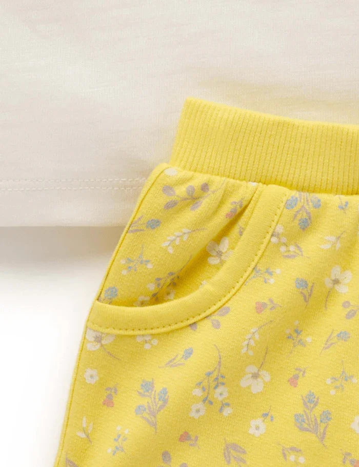 Close-up of yellow floral baby pants with elastic waistband and side pocket detail