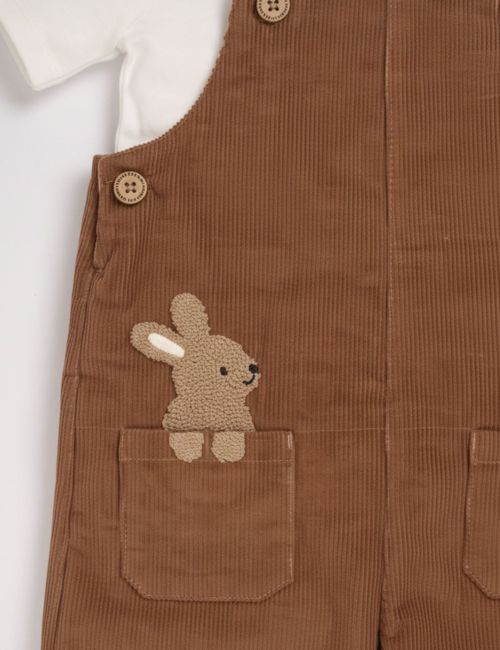 Macro close-up of the organic cotton brown corduroy fabric featuring a textured bunny pocket detail.