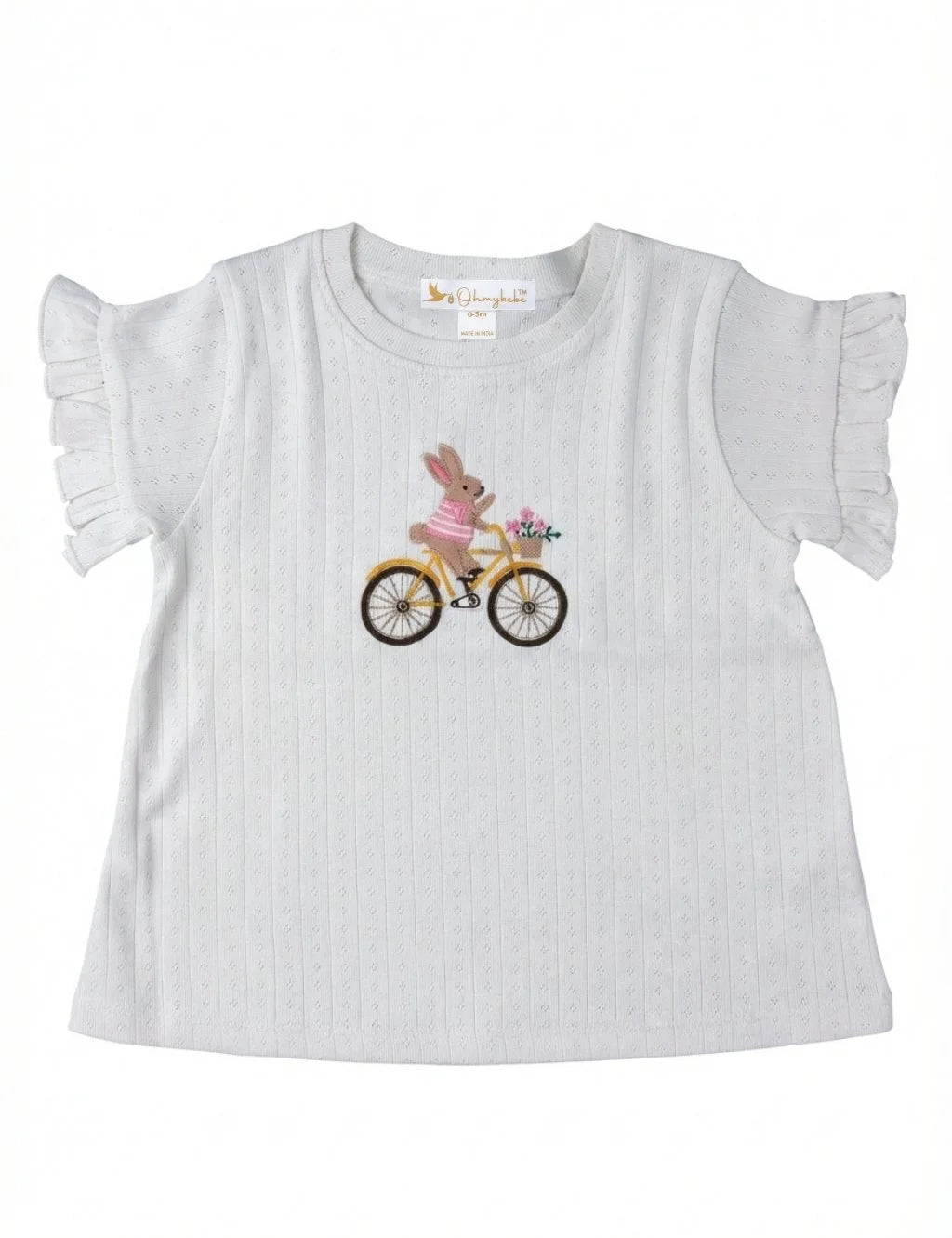 Flatlay of an organic cotton white ruffled-sleeve top featuring an embroidered bunny riding a yellow bicycle