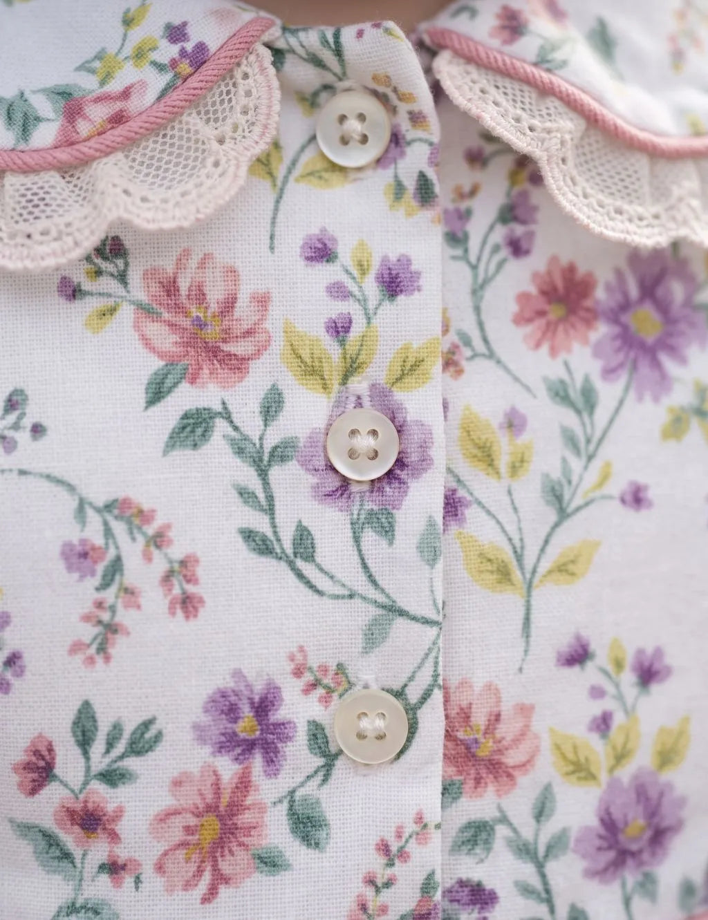 Close-up of the organic cotton floral print fabric, front buttons, and pink lace-trimmed collar.   