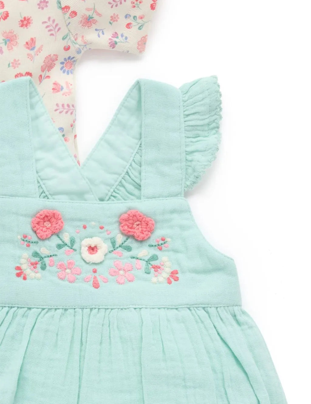 Close-up of the embroidered floral chest detailing and ruffled straps on the organic cotton mint green onesie.