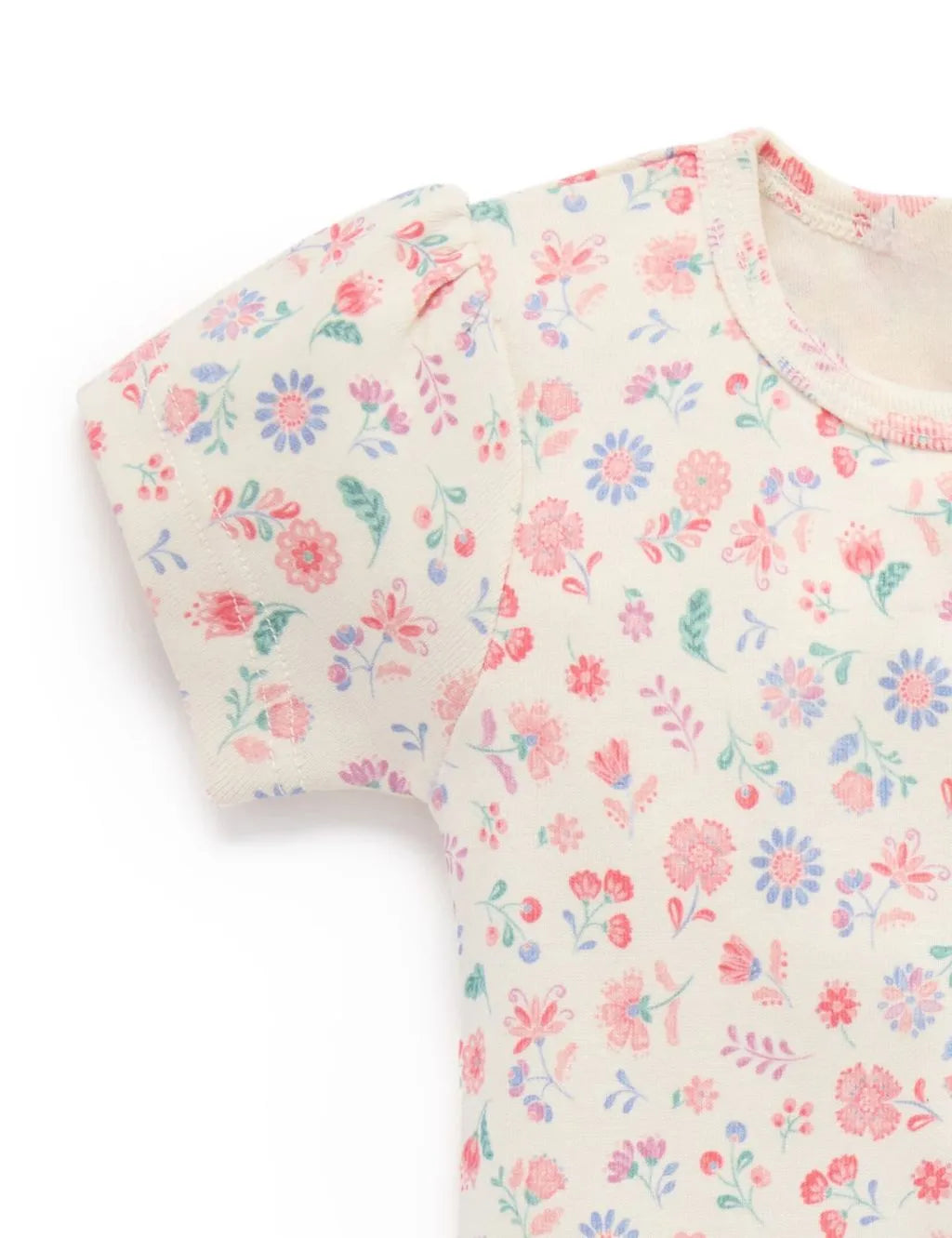 Close-up of the delicate floral pattern and puff sleeve on the organic cotton top.