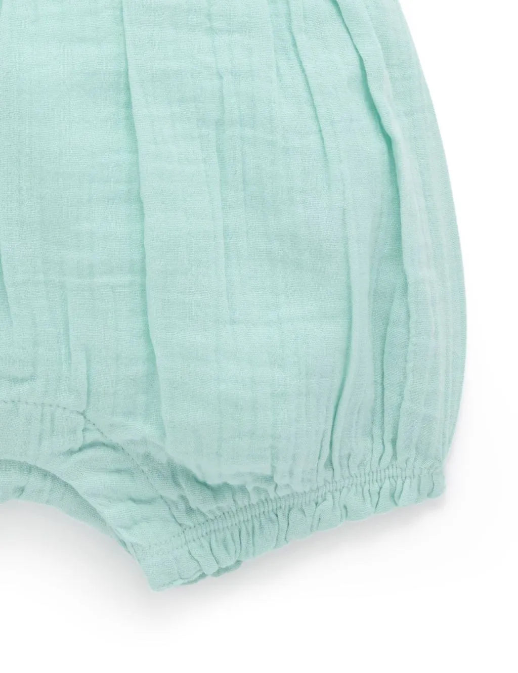Close-up of the textured fabric and elasticated leg openings on the organic cotton mint green onesie.