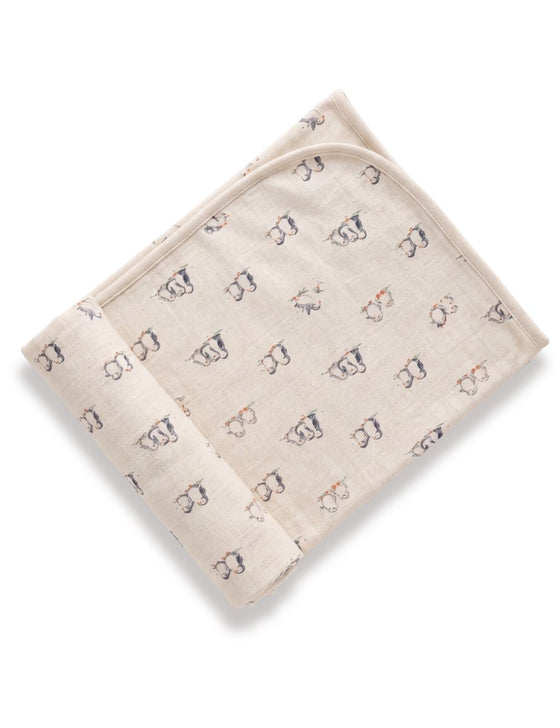 Folded organic cotton baby swaddle blanket featuring a playful penguin print pattern