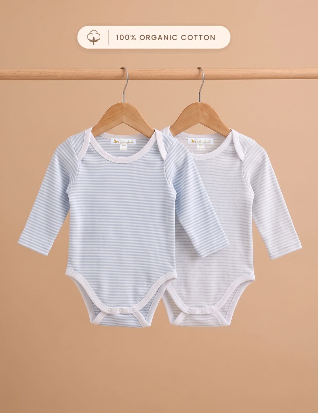 Pack of two organic cotton long-sleeve striped onesies hanging on wooden hangers.