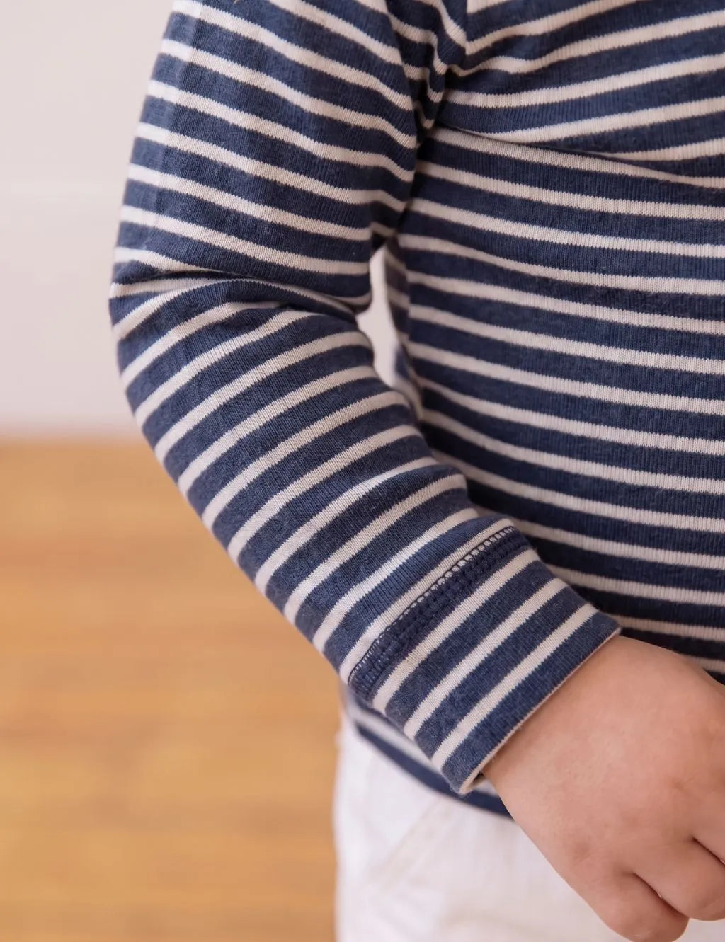 Macro close-up showing the soft organic cotton fabric and navy-and-white stripe pattern on the sleeve.